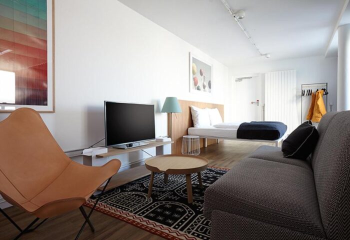 Generator Berlin Mitte gay-friendly hotel room. Modern decor with bed, sofa, TV, and stylish furniture. A comfortable stay in Berlin, Germany.