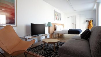 Generator Berlin Mitte gay-friendly hotel room. Modern decor with bed, sofa, TV, and stylish furniture. A comfortable stay in Berlin, Germany.