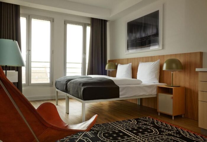 Generator Berlin Mitte gay-friendly hotel room. Modern design with twin beds, stylish decor, and a comfortable chair. Perfect for gay travelers.