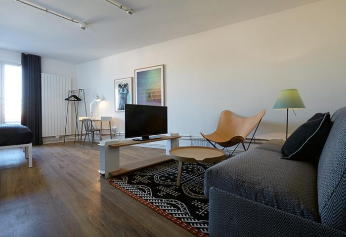 Generator Berlin Mitte hotel room. Gay-friendly travel destination with modern decor: TV, sofa, desk, and butterfly chair. Stylish, comfortable.