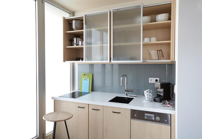 Generator Berlin Mitte hotel kitchenette. Gay-friendly hotel room with sink, cabinets, coffee maker, and stool. Modern design, ideal for gay travel.