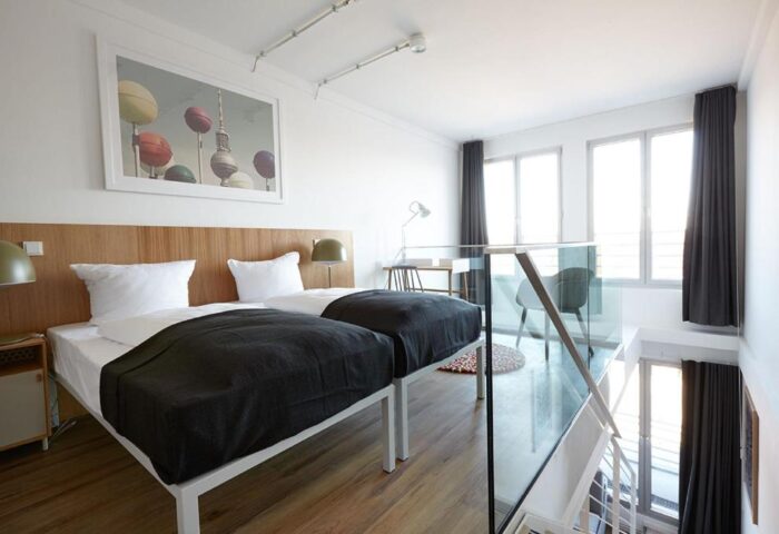 Generator Berlin Mitte gay-friendly hotel room. Two beds, desk, and glass railing. Interior design, modern style. Great for gay travel.