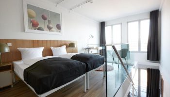 Generator Berlin Mitte gay-friendly hotel room. Two beds, desk, and glass railing. Interior design, modern style. Great for gay travel.