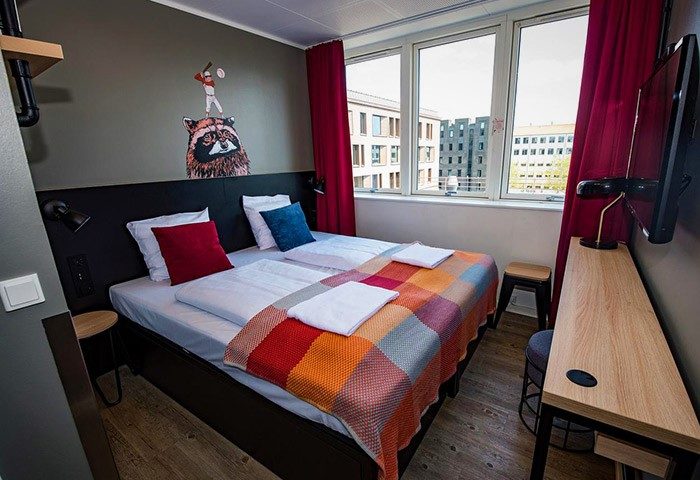Generator Copenhagen hotel room with double bed, colorful blanket, and window view. Gay-friendly stay with modern design. #CopenhagenHotel