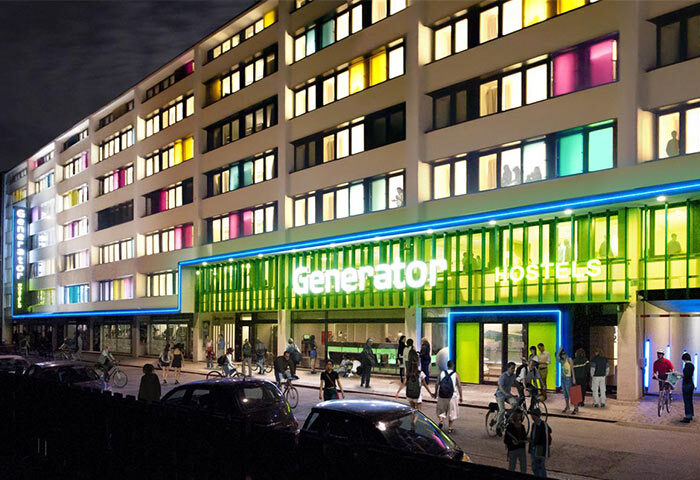 Generator Copenhagen, a gay-friendly hotel. Exterior view at night with colorful windows and people walking outside. Great for gay travelers.