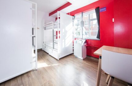 Generator London gay-friendly hotel room. Bunk beds, red wall, sink, and table. Pet-friendly stay in London, England. Modern hostel.