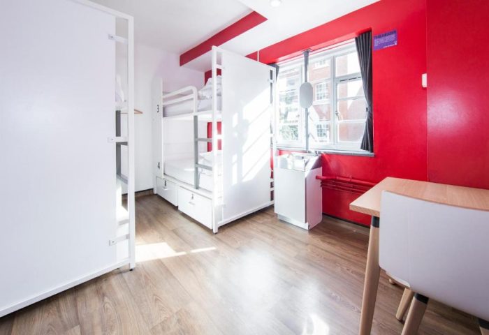 Generator London gay-friendly hotel room. Bunk beds, red wall, sink, and table. Pet-friendly stay in London, England. Modern hostel.