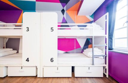 Generator London gay-friendly hotel: Dorm room with bunk beds, lockers, and colorful geometric wall design. Pet-friendly hostel in London.