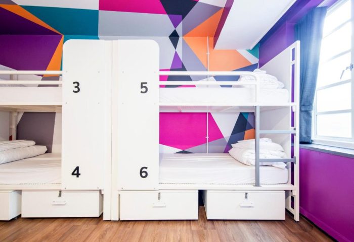 Generator London gay-friendly hotel: Dorm room with bunk beds, lockers, and colorful geometric wall design. Pet-friendly hostel in London.