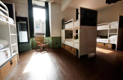 Generator Rome gay-friendly hotel room. Bunk beds with numbered storage, a wicker chair, and a window with green curtains. Modern hostel.