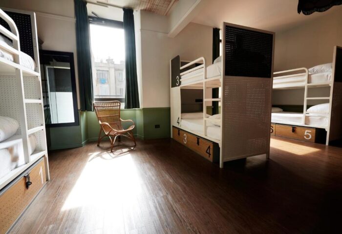 Generator Rome gay-friendly hotel room. Bunk beds with numbered storage, a wicker chair, and a window with green curtains. Modern hostel.