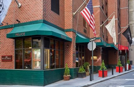 Gild Hall, A Thompson Hotel By Hyatt facade. Gay-friendly hotel with Felice restaurant. Flags, including the US flag, fly outside.