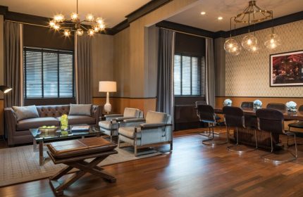 Gild Hall, A Thompson Hotel By Hyatt interior. Gay-friendly hotel lounge with sofa, chairs, and a dining table. Elegant lighting fixtures.