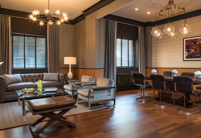 Gild Hall, A Thompson Hotel By Hyatt interior. Gay-friendly hotel lounge with sofa, chairs, and a dining table. Elegant lighting fixtures.
