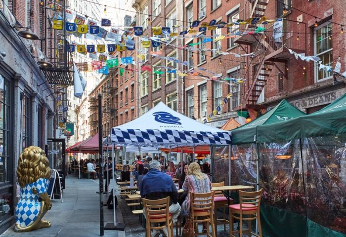 Outdoor dining at Gild Hall, A Thompson Hotel By Hyatt. A gay-friendly hotel in NYC, with tents, flags, and a lion statue.