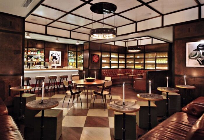 Gild Hall, A Thompson Hotel By Hyatt bar interior. Gay-friendly hotel with leather seating, checkered floors, and a well-stocked bar.