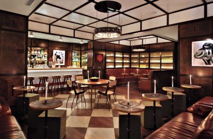Gild Hall, A Thompson Hotel By Hyatt bar interior. Gay-friendly hotel with leather seating, checkered floors, and a well-stocked bar.