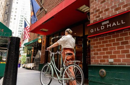 Gild Hall, A Thompson Hotel by Hyatt entrance. Woman with bike. Gay-friendly hotel in NYC, near Financial District. Travel advice for gay men.