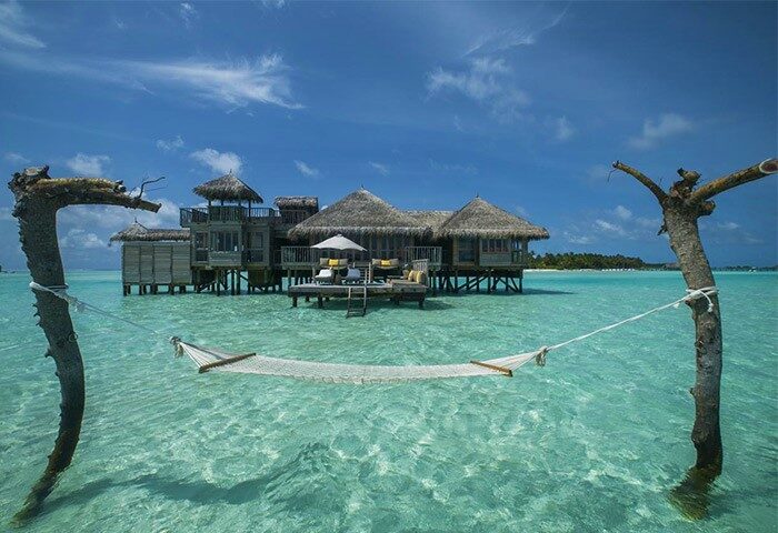 Gili Lankanfushi Maldives gay-friendly hotel: Overwater bungalow with hammock in turquoise water. Perfect for gay men's luxury travel.
