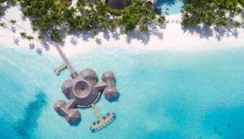 Aerial view of Gili Lankanfushi, Maldives. Gay-friendly hotel with overwater bungalows, white sand beach, and turquoise water. Tropical paradise.