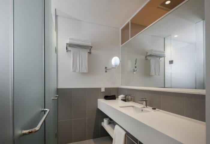Glad Live Gangnam hotel bathroom. Modern design with white sink, large mirror, and shower. Gay-friendly hotel in Seoul, South Korea.