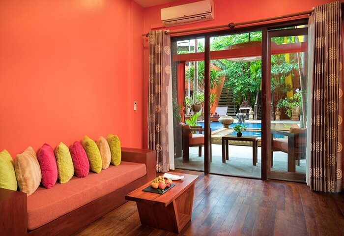 Golden Temple Hotel room with pool view. Gay-friendly hotel with colorful pillows, wood floors, and outdoor access. Perfect for gay travel.