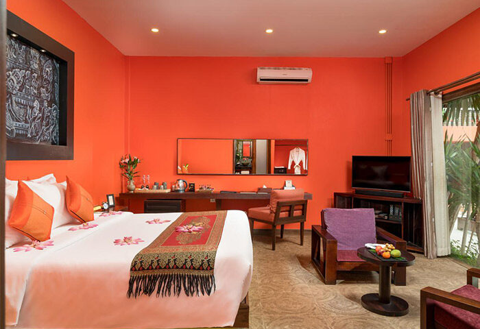 Gay-Friendly Golden Temple Hotel room. Orange walls, a bed with flower petals, & seating area. Ideal for gay men travel. Siem Reap hotel.