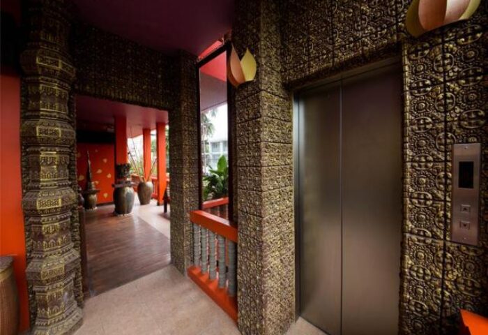 Golden Temple Hotel's ornate elevator. This gay-friendly hotel features unique decor, with carved pillars and patterned walls, creating a luxurious stay.