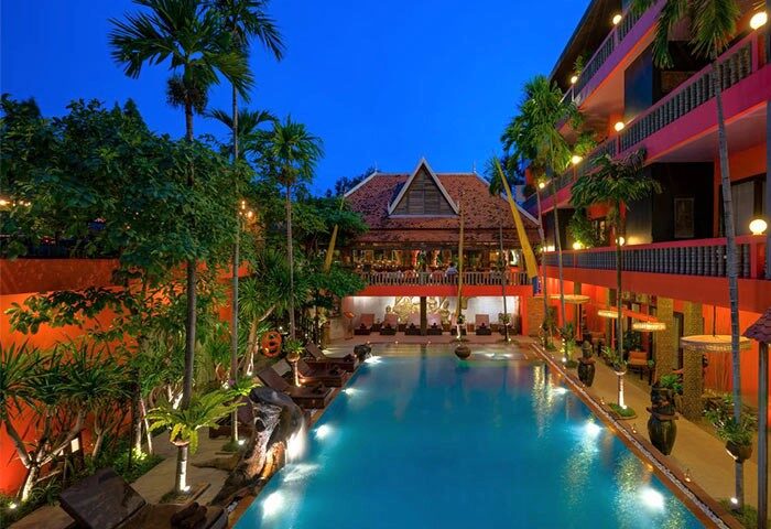 Golden Temple Hotel pool view at dusk. Gay-friendly hotel with tropical plants and lounge chairs. Perfect for gay men's travel.