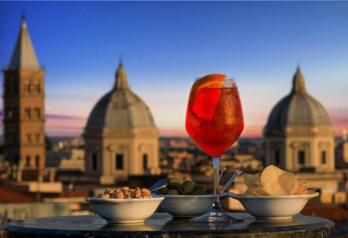 Golden Tulip Rome Piram gay-friendly hotel rooftop bar. Aperol spritz, snacks, and Rome skyline view. Gay travel in Rome.
