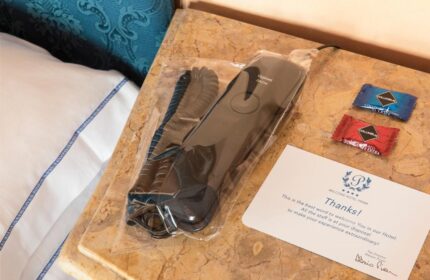 Golden Tulip Rome Piram hotel room detail: phone in plastic wrap, chocolates, and a welcome card. Gay-friendly hotel amenities for a comfortable stay.