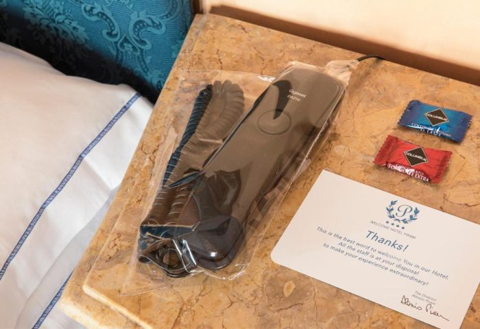 Golden Tulip Rome Piram hotel room detail: phone in plastic wrap, chocolates, and a welcome card. Gay-friendly hotel amenities for a comfortable stay.