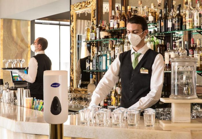 Bar at the Gay-Friendly Golden Tulip Rome Piram hotel. Bartender in mask prepares drinks. Safe & stylish travel for gay men in Rome.