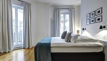 Gorki Apartments bedroom: Gay-friendly, pet-friendly hotel. Modern design, light walls, wood floor, bed with blue throw, & balcony access.