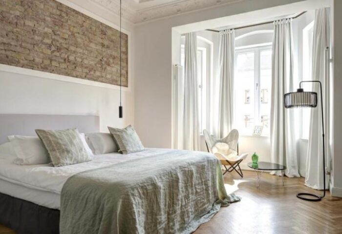 Gorki Apartments pet-friendly room. Gay-friendly hotel bedroom with brick wall, bed, chair, and floor lamp. Modern, bright, and stylish design.
