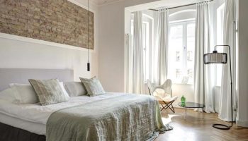Gorki Apartments pet-friendly room. Gay-friendly hotel bedroom with brick wall, bed, chair, and floor lamp. Modern, bright, and stylish design.