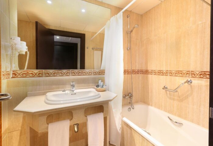 Bathroom at Gran Hotel Cervantes by Blue Sea, a gay-friendly hotel. Sink, mirror, bathtub, shower, and towels. Great for gay travel.