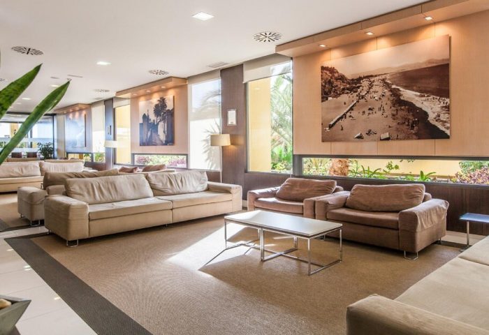 Gran Hotel Cervantes by Blue Sea lobby. Gay-friendly hotel seating area with couches, chairs, and beach-themed art. Ideal for gay travel.