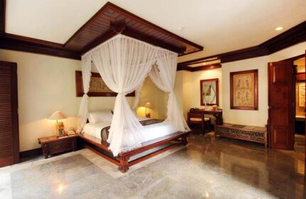 Grand Balisani Suites Hotel room. Gay-friendly hotel with a four-poster bed, desk, and marble floor. Luxury Bali travel for gay men.