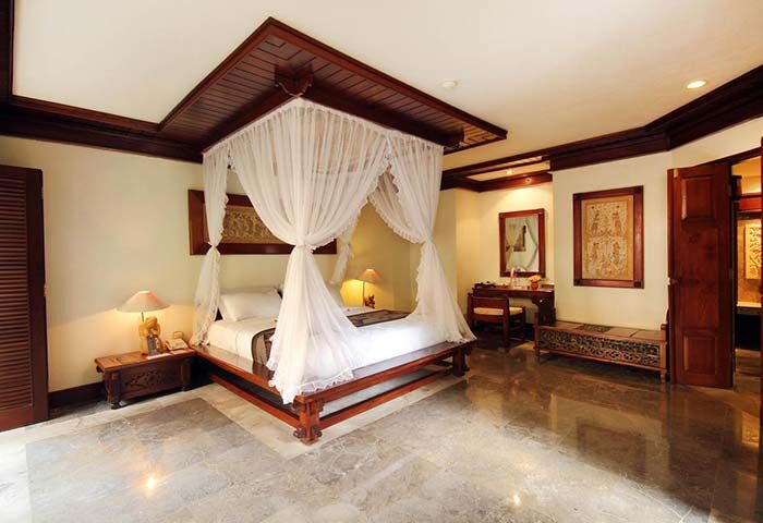 Grand Balisani Suites Hotel room. Gay-friendly hotel with a four-poster bed, desk, and marble floor. Luxury Bali travel for gay men.