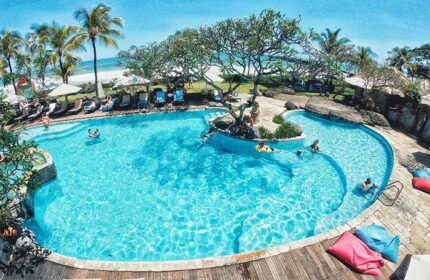 Grand Balisani Suites Hotel pool view. Gay-friendly hotel with palm trees, beach, and clear blue water. Perfect for gay travel advice.