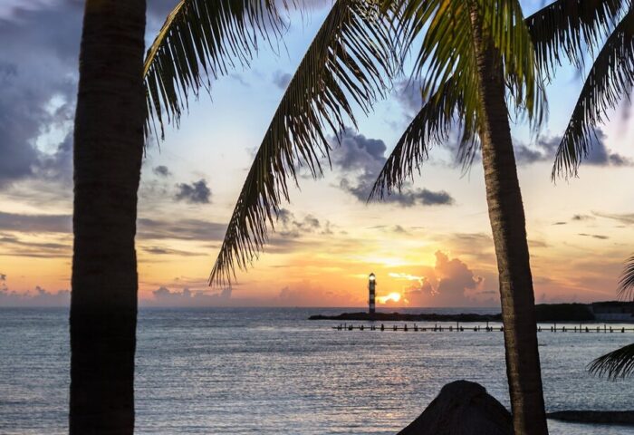 Romantic beach dinner at Grand Fiesta Americana Coral Beach Cancun, a gay-friendly all-inclusive hotel. Sunset view with palm trees and lanterns.