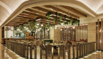 Grand Fiesta Americana Coral Beach Cancun All Inclusive gay-friendly hotel restaurant. Hanging lights and plants above tables, horse statue.