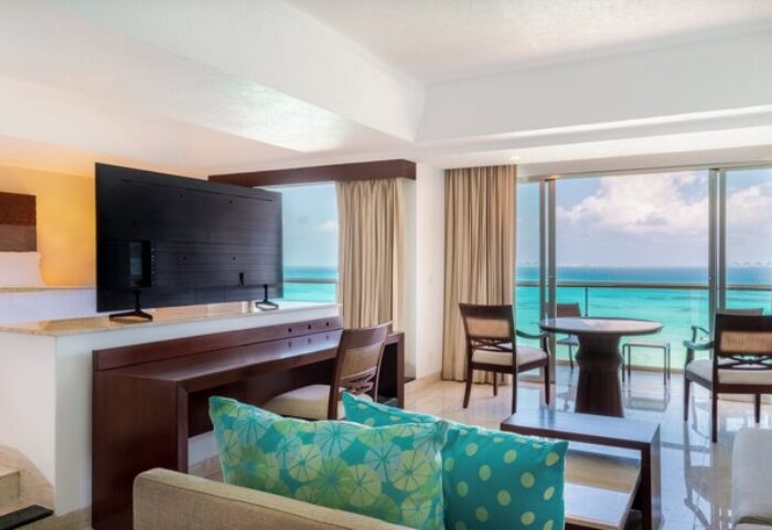 Grand Fiesta Americana Coral Beach Cancun suite. Gay-friendly hotel all-inclusive room with ocean view, bed, desk, living area, balcony.