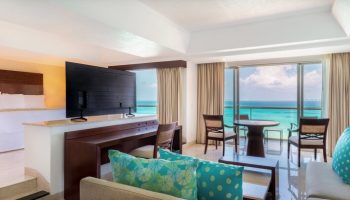 Grand Fiesta Americana Coral Beach Cancun suite. Gay-friendly hotel all-inclusive room with ocean view, bed, desk, living area, balcony.