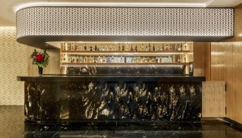 Bar at Grand Fiesta Americana Coral Beach Cancun All Inclusive, a gay-friendly hotel. Marble counter, liquor shelves, & patterned decor.