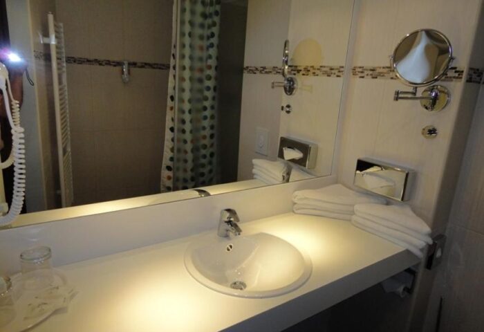 Bathroom at Grand Hotel Dream Main City Center, a gay-friendly hotel. Sink, mirror, and shower curtain visible.