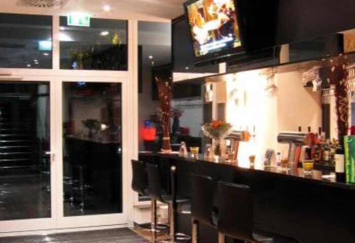 Grand Hotel Dream Main City Center bar area. Gay-friendly hotel bar with stools, TV, and drinks. Modern design for gay travelers.