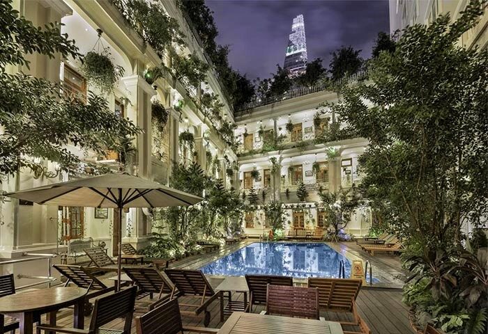 Grand Hotel Saigon pool area. Gay-friendly hotel with city view, plants, tables, chairs, and a pool. Ideal for gay travelers in Saigon.