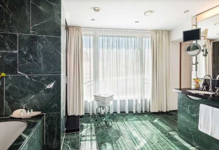 Grand Hyatt Berlin gay-friendly hotel bathroom. Green marble, white towels, and bright window. A luxurious experience for gay travelers.